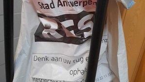 A white paper bag hanging from a red and black metal stand. - Room-private Room Antwerpen (Antwerp)