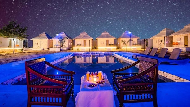 A nighttime resort with a swimming pool, lounge chairs, and tents under a starry sky. - Desert Stay Camping Jaisalmer (Jaisalmer)