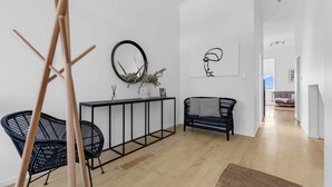 A modern living room with a black console table, a black wicker chair, and a black sofa. - Stanley Bay Apartment, Devonport (Stanley Point)