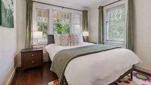 Ein Schlafzimmer mit Bett, Nachttischen und einem Fenster mit Vorhängen.