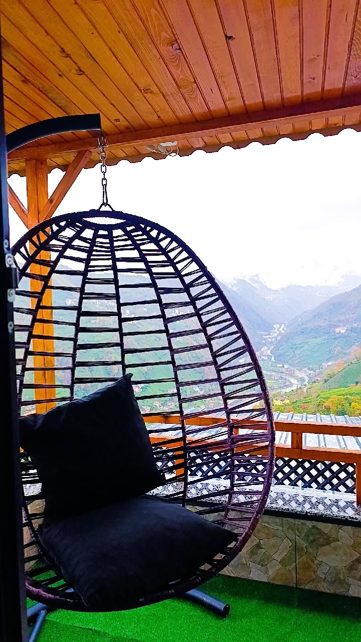 Una silla colgante con cojín en un balcón con vistas a las montañas.