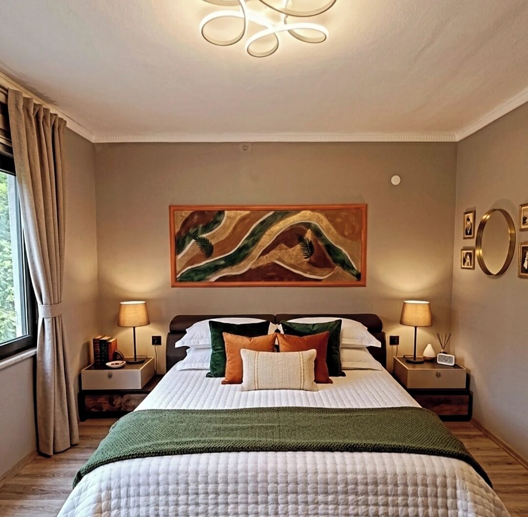 A bedroom with a bed, two bedside tables, a painting, and a window with curtains.