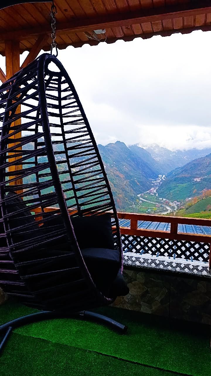 A hanging chair with a view of a mountainous landscape.