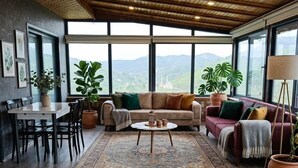 Un'ampia zona giorno con soffitto in legno, ampie finestre, un divano, un tavolo da pranzo e un tavolino da caffè.