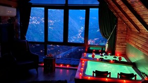 Een gezellige kamer met een groot raam, een pooltafel en uitzicht op een bergachtig landschap.