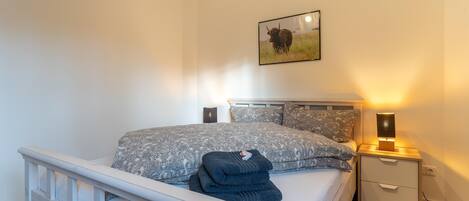 Quarto com cama, mesas de cabeceira e um quadro na parede.