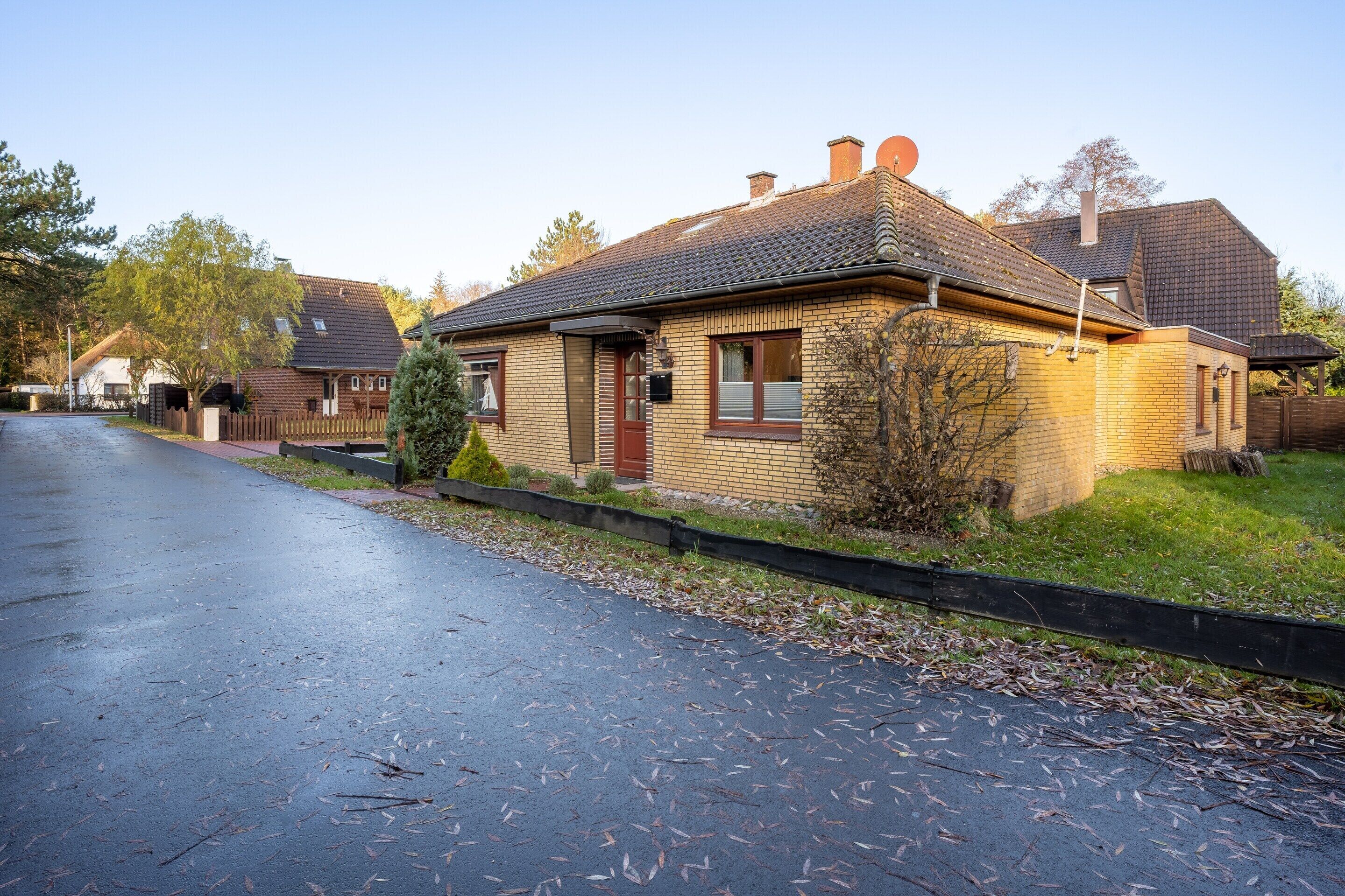 A residential house with a brick exterior, a tiled roof, and a front yard.