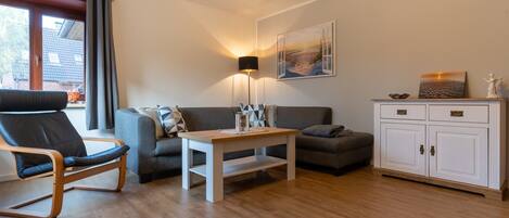 Un salon moderne comprenant un canapé, un fauteuil, une table basse et un meuble.