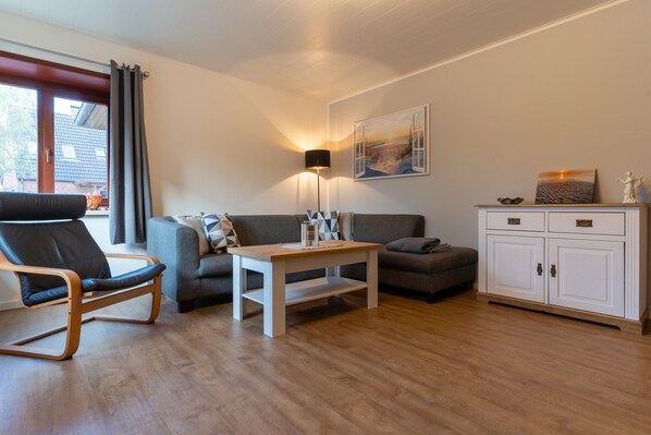 Una sala moderna con un sofá, un sillón, una mesa de centro y un aparador.