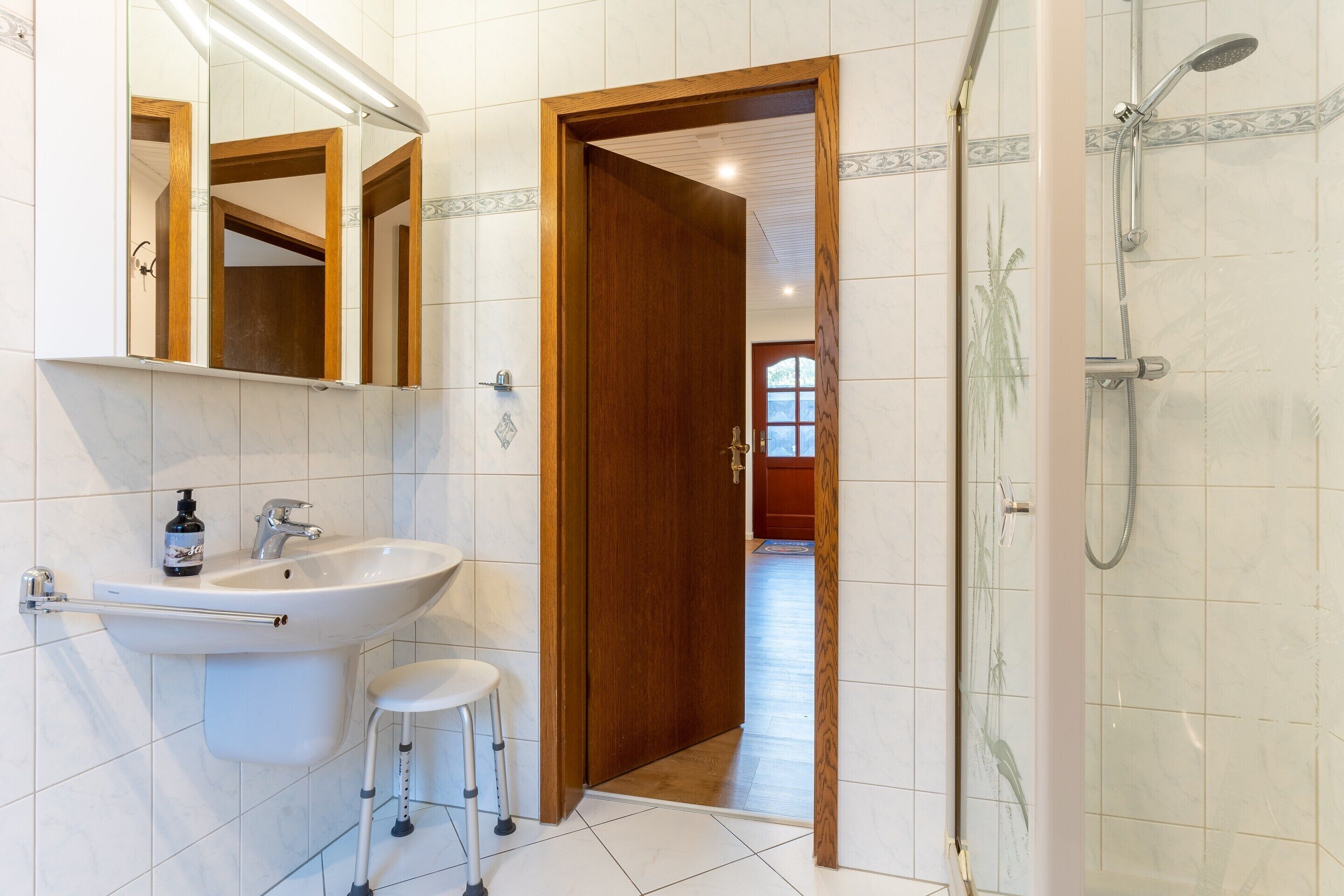 A bathroom with a sink, mirror, and shower.