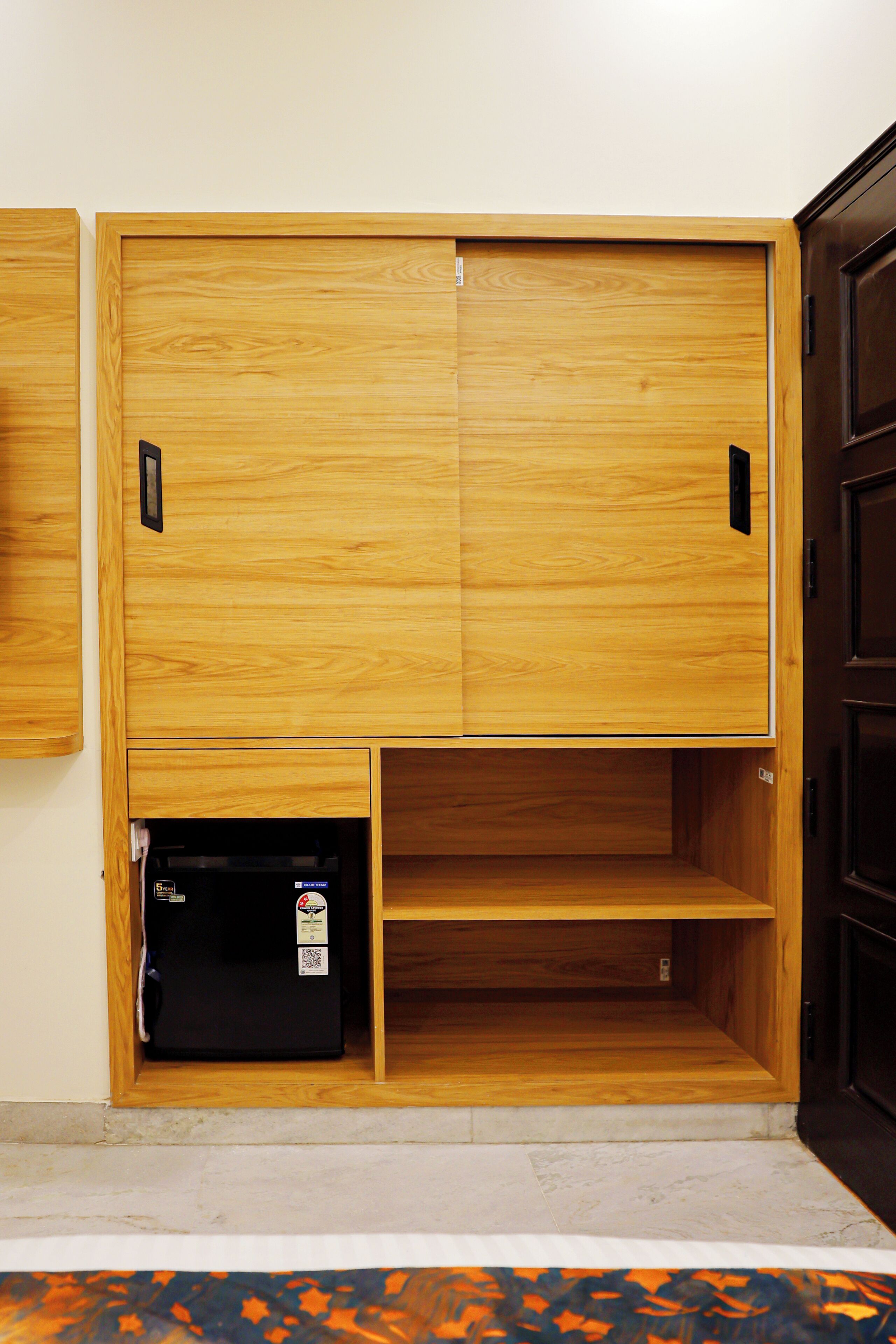 Un armario de madera con dos puertas y un estante inferior.