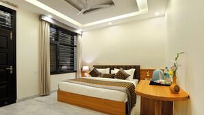 A modern bedroom with a wooden bed, a bedside table, and a nightstand. - OPO Essential Sec 21 (Gurugram)