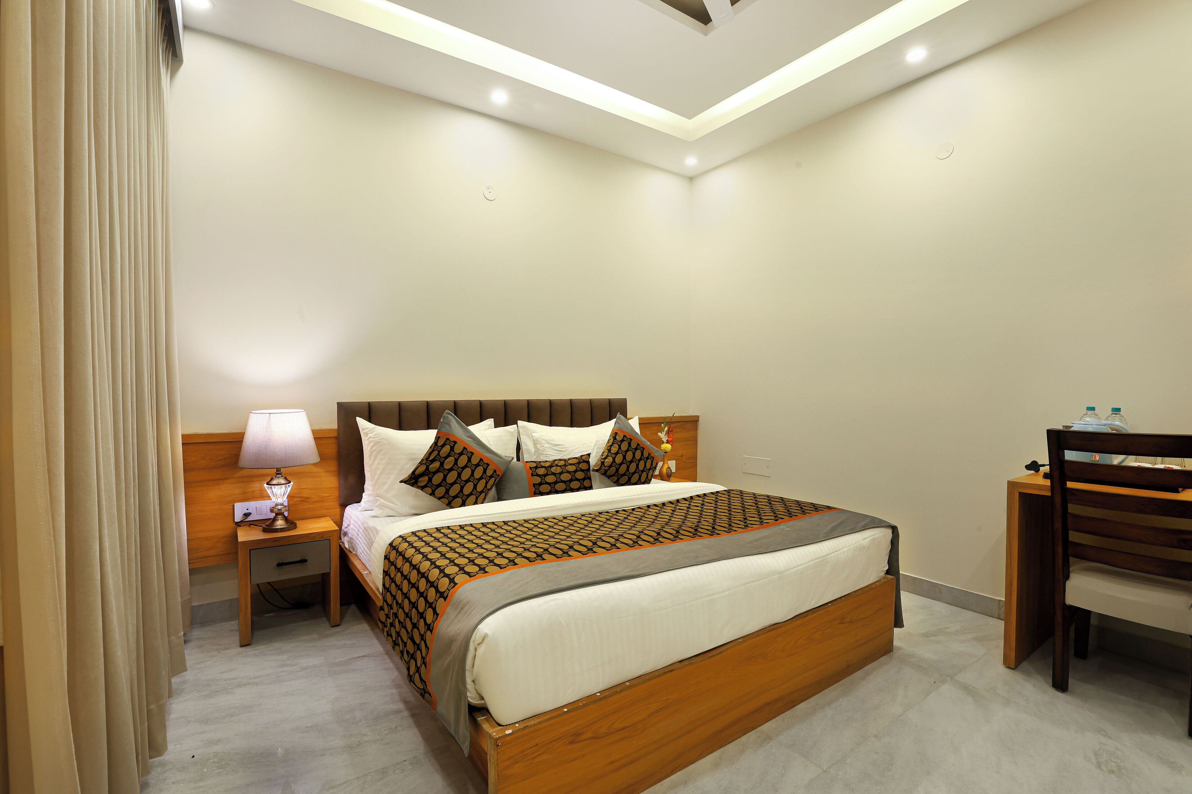 Una habitación de hotel con cama, mesita de noche, lámpara y una silla.