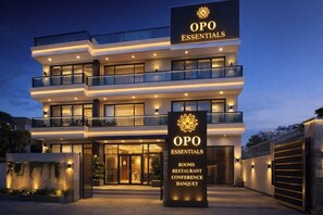A multi-story hotel with a sign indicating it offers rooms, a restaurant, conference facilities, and a banquet hall.