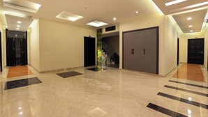 A spacious hallway with a marble floor, recessed lighting, and a staircase leading to an upper level. - OPO Essential Sec 21 (Gurugram)