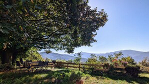 A dining area with a table and chairs, surrounded by greenery and a view of distant mountains. - Rural cottage in Vosges, 6 pers., WiFi, parking, bikes welcome (Fresse-sur-Moselle)