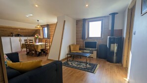 A cozy living room with a sofa, a TV, a fireplace, and a dining area with a table and chairs. - Rural cottage in Vosges, 6 pers., WiFi, parking, bikes welcome (Fresse-sur-Moselle)