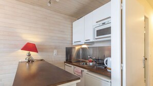 A compact kitchen with white cabinets, a stainless steel sink, a microwave, and a small refrigerator.