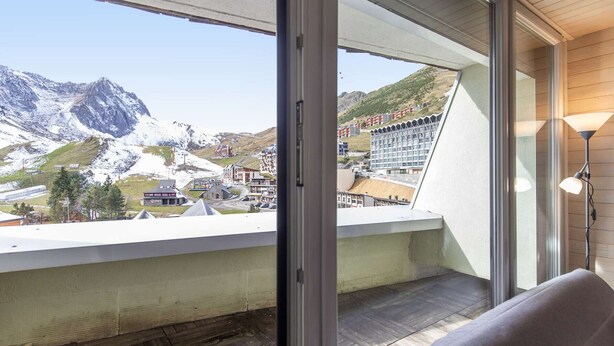 A balcony with a view of a mountainous landscape, a modern building, and a lamp.