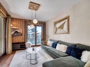 Ein modernes Wohnzimmer mit einem grünen Sofa, einem runden Couchtisch und einer Holzbalkendecke.