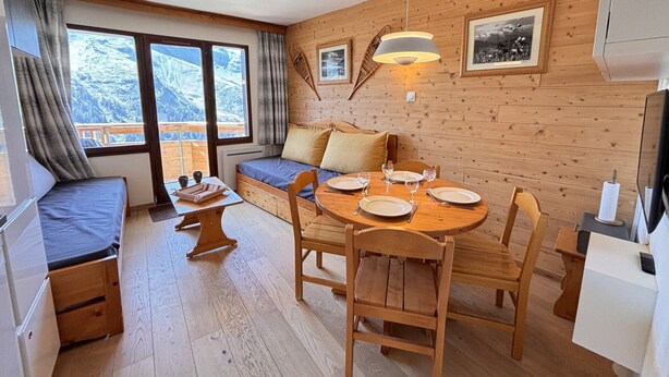 Una habitación acogedora con una cama, una mesa de comedor para cuatro personas y un sofá.