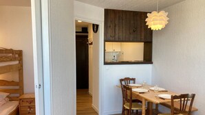 A compact room with a bunk bed, a dining table with chairs, and a hanging light fixture.