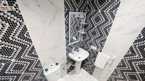 Un baño con inodoro, lavabo y espejo. Las paredes están cubiertas con un patrón de cuadros blancos y negros.
