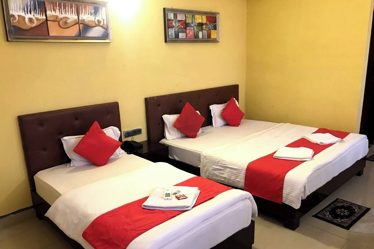 A hotel room with two beds, each with red and white bedding, and a small table between them.