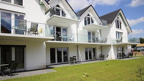 A modern two-story house with a balcony, large windows, and a well-maintained lawn. - Appartement Hafenflair am Plauer See (Plau am See)