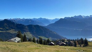 A mountainous landscape with a clear sky, a lake, and several houses with sloped roofs. - Berggasthaus Rigi Burggeist (Gersau)