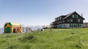 A two-story building with a sloped roof, green shutters, and a balcony. - Berggasthaus Rigi Burggeist (Gersau)