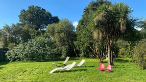A grassy outdoor area with two white lounge chairs and two red chairs. - Charming Holiday Home With Garden in the Cotentin (Fierville-les-Mines)