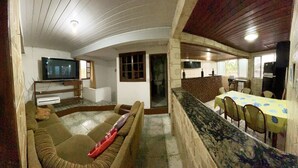 A living room with a TV, sofa, and dining area with chairs and a table. - Pousada da Praia Frade (Angra dos Reis)