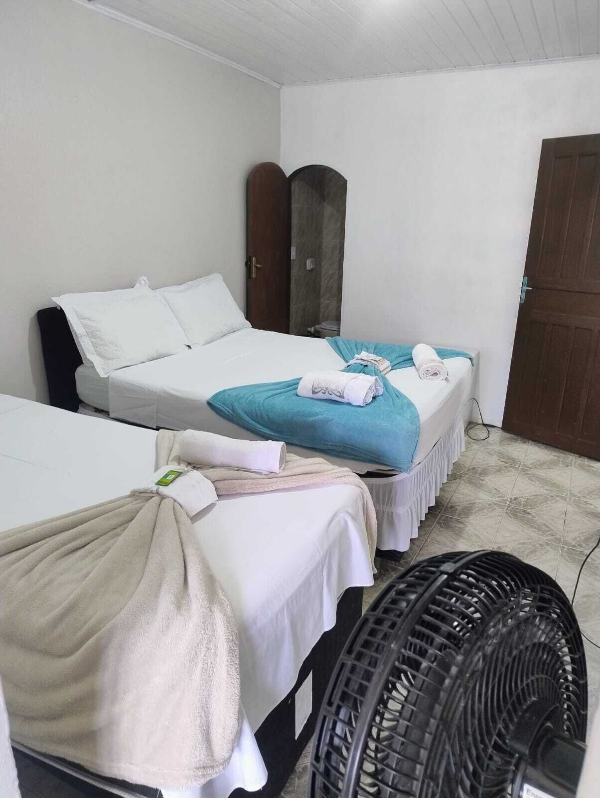 A hotel room with two beds, a fan, and a wooden door.