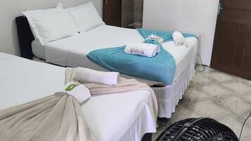 A hotel room with two beds, a fan, and a wooden door.