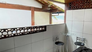 A compact kitchen with a sink, two stools, a small table, and a stove. - Pousada da Praia Frade (Angra dos Reis)