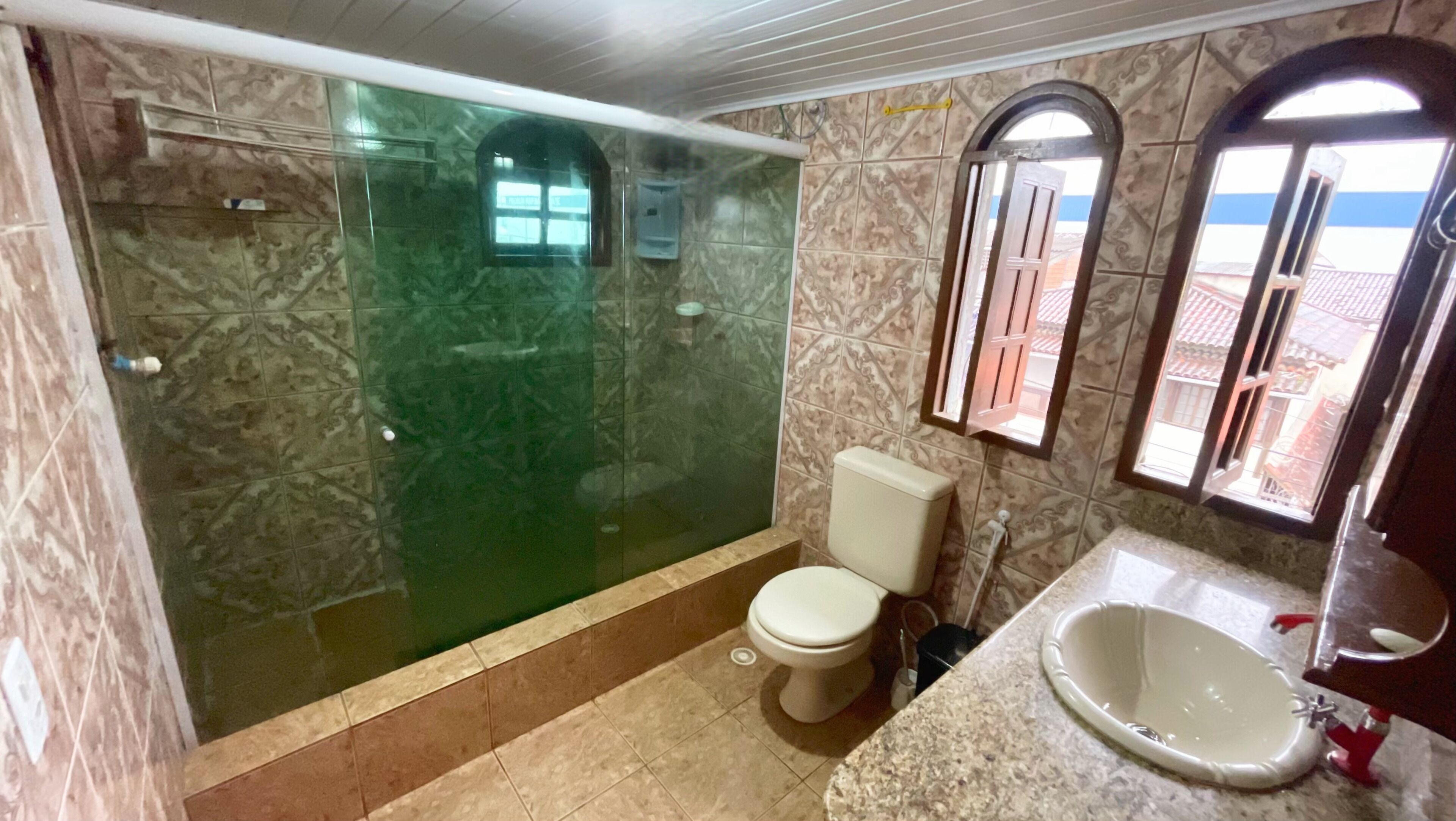 Une salle de bain avec une douche à parois de verre, des toilettes et un lavabo.