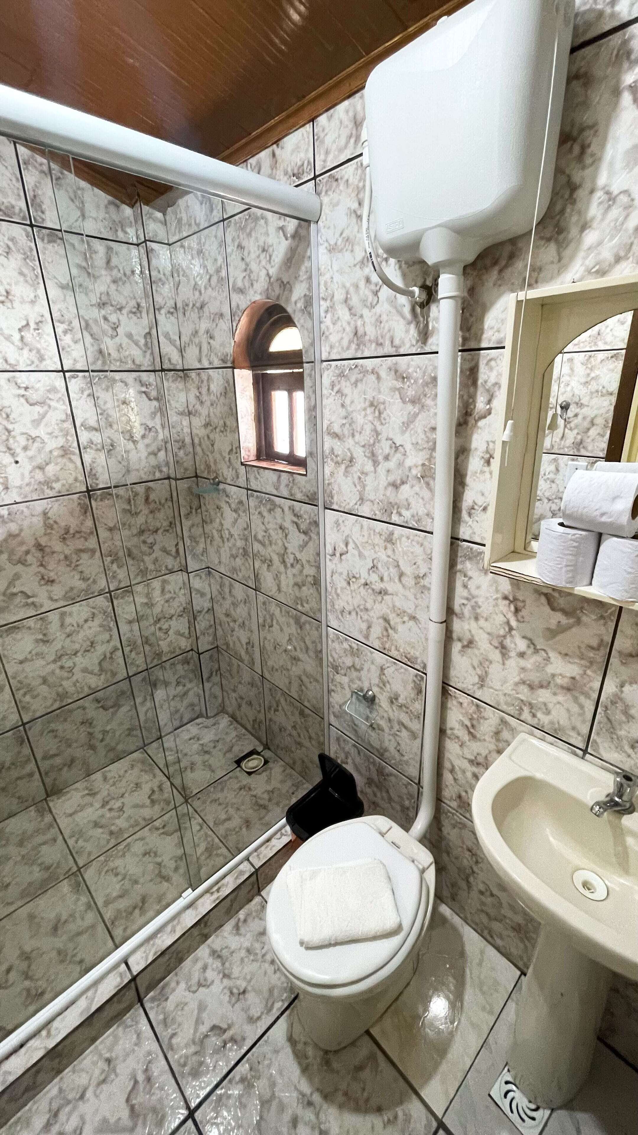 A bathroom with a toilet, bidet, and sink, all with marble tile walls.