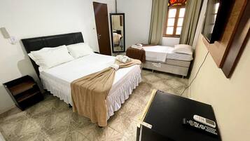 A hotel room with a large bed, a smaller bed, a desk with a TV, and a mirror.