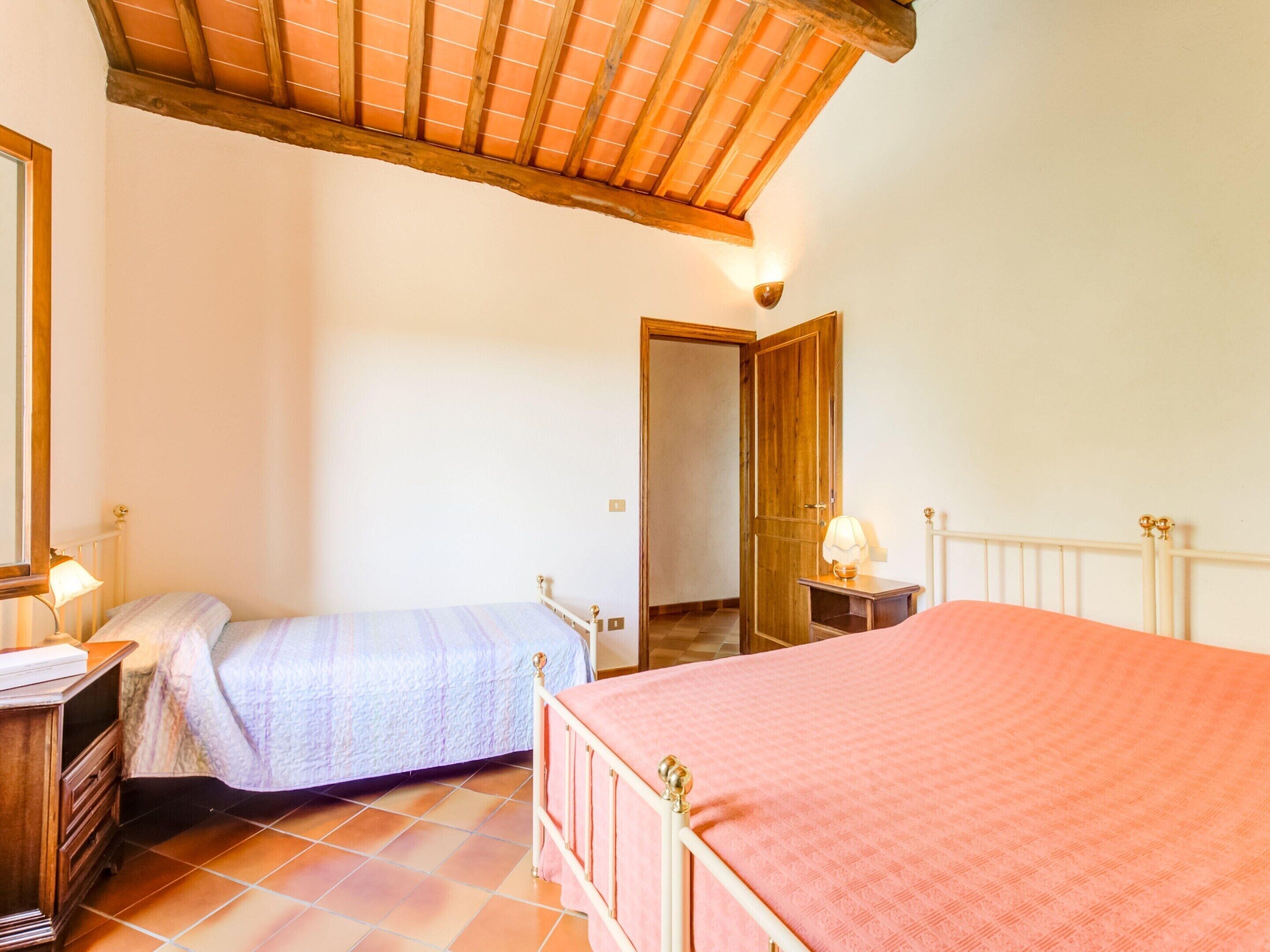 A bedroom with two beds, a wooden ceiling, a wardrobe, and a mirror.