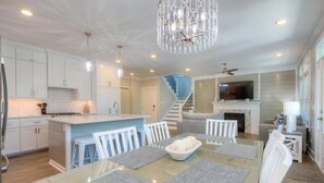 A spacious living area with a dining table, chairs, and a chandelier.