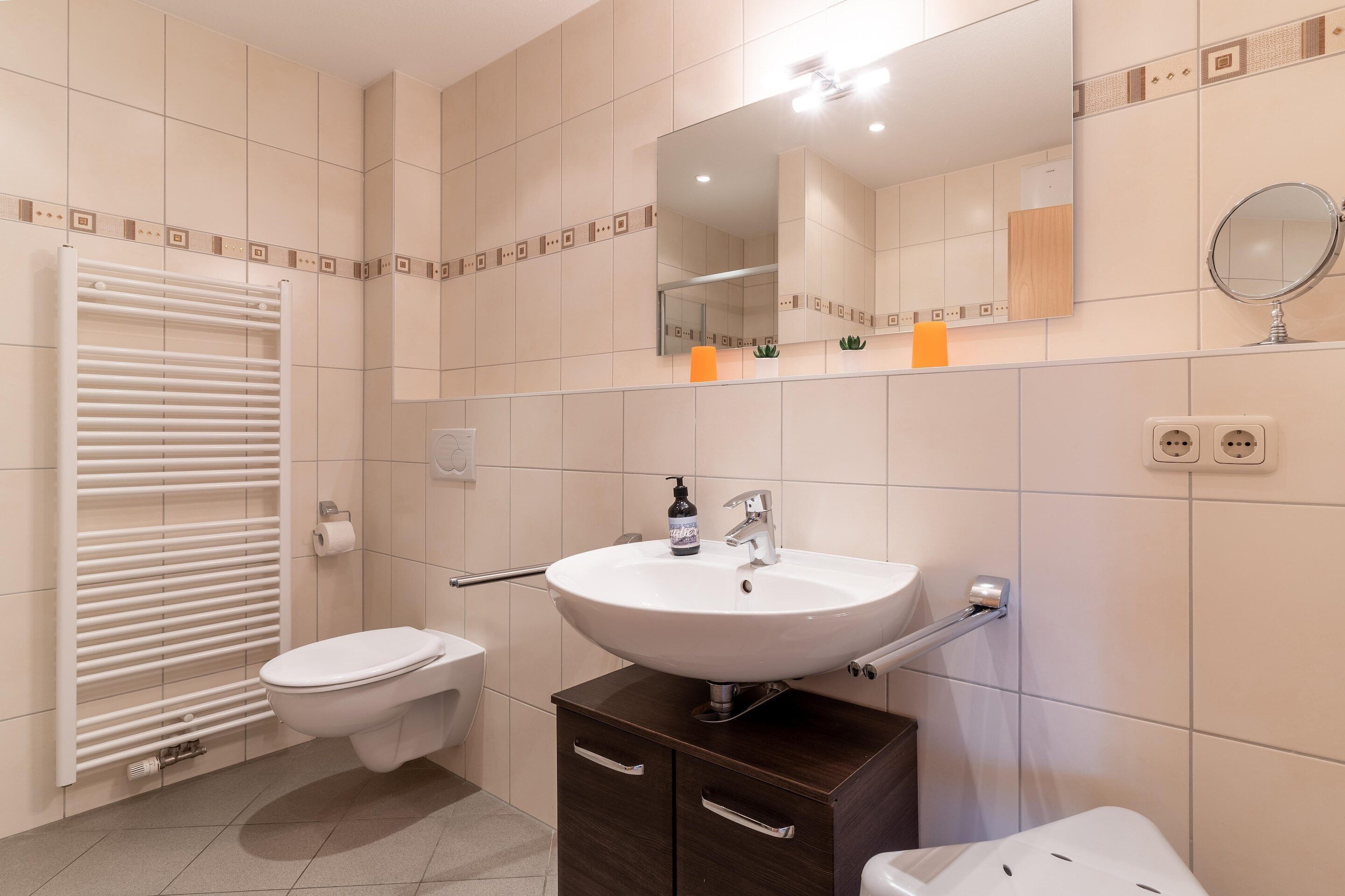 A modern bathroom with a white sink, toilet, and towel rack.