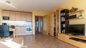 Eine moderne Küche mit Holzschränken, einer eingebauten Mikrowelle und einem Essbereich mit Tisch und Stühlen.