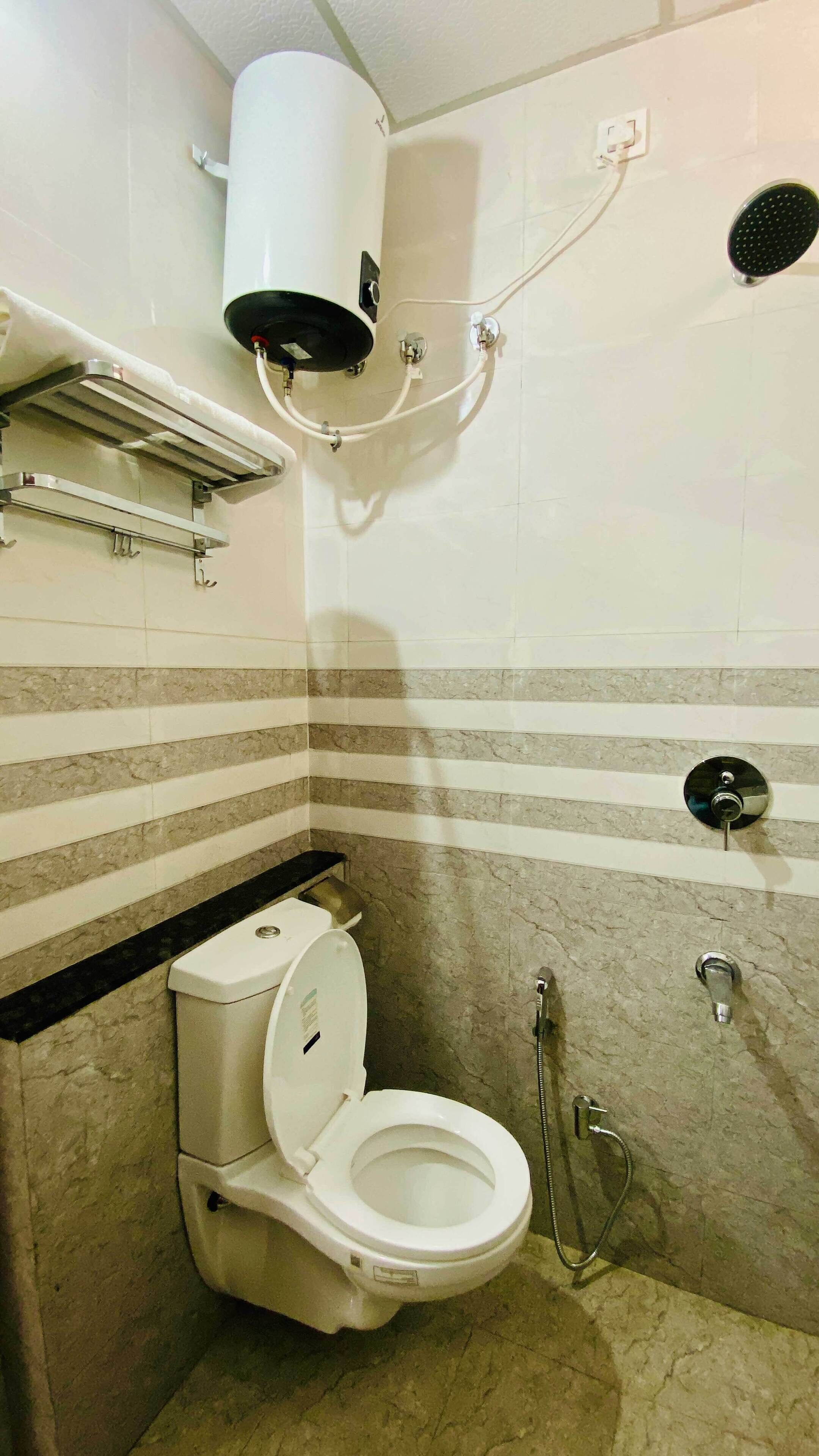Un baño pequeño y moderno con inodoro, ducha y perchero para toallas.