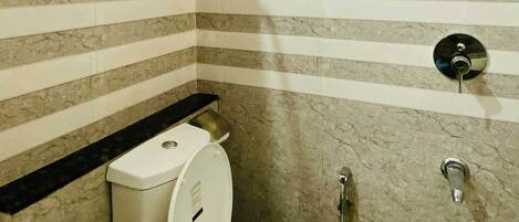Un baño pequeño y moderno con inodoro, ducha y perchero para toallas.