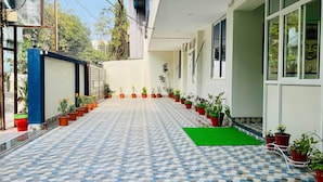 Un espace extérieur abrité, doté d’un sol carrelé à motifs, de plantes en pot et d’un tapis vert.