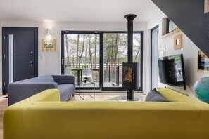 A modern living room with a sofa, a television, and a fireplace. - Holiday Home by Lake Wiselka With Sauna (gmina Wolin)