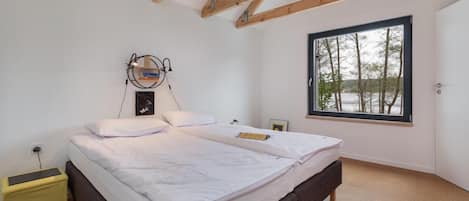 A bedroom with a large bed, a window with a view of trees, and a wooden ceiling.