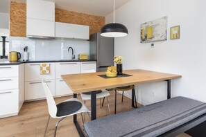 A modern kitchen with white cabinets, a wooden dining table, and a bench. - Holiday Home by Lake Wiselka With Sauna (gmina Wolin)