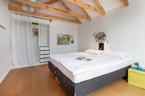 Ein Schlafzimmer mit einem Bett, einem Kleiderschrank, einem Schreibtisch und einer Pflanze.